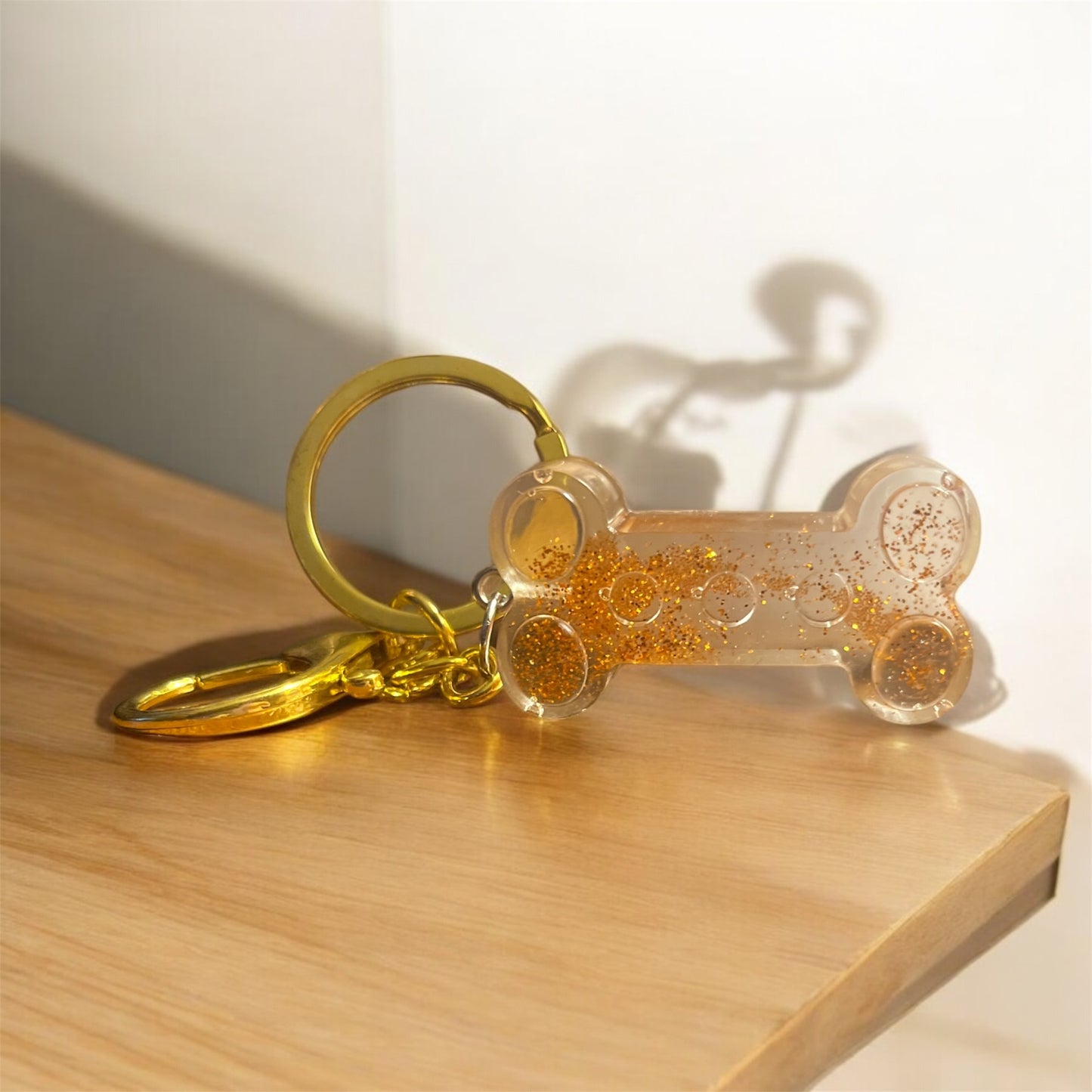 Dog bone keychain - clear with orange glitter
